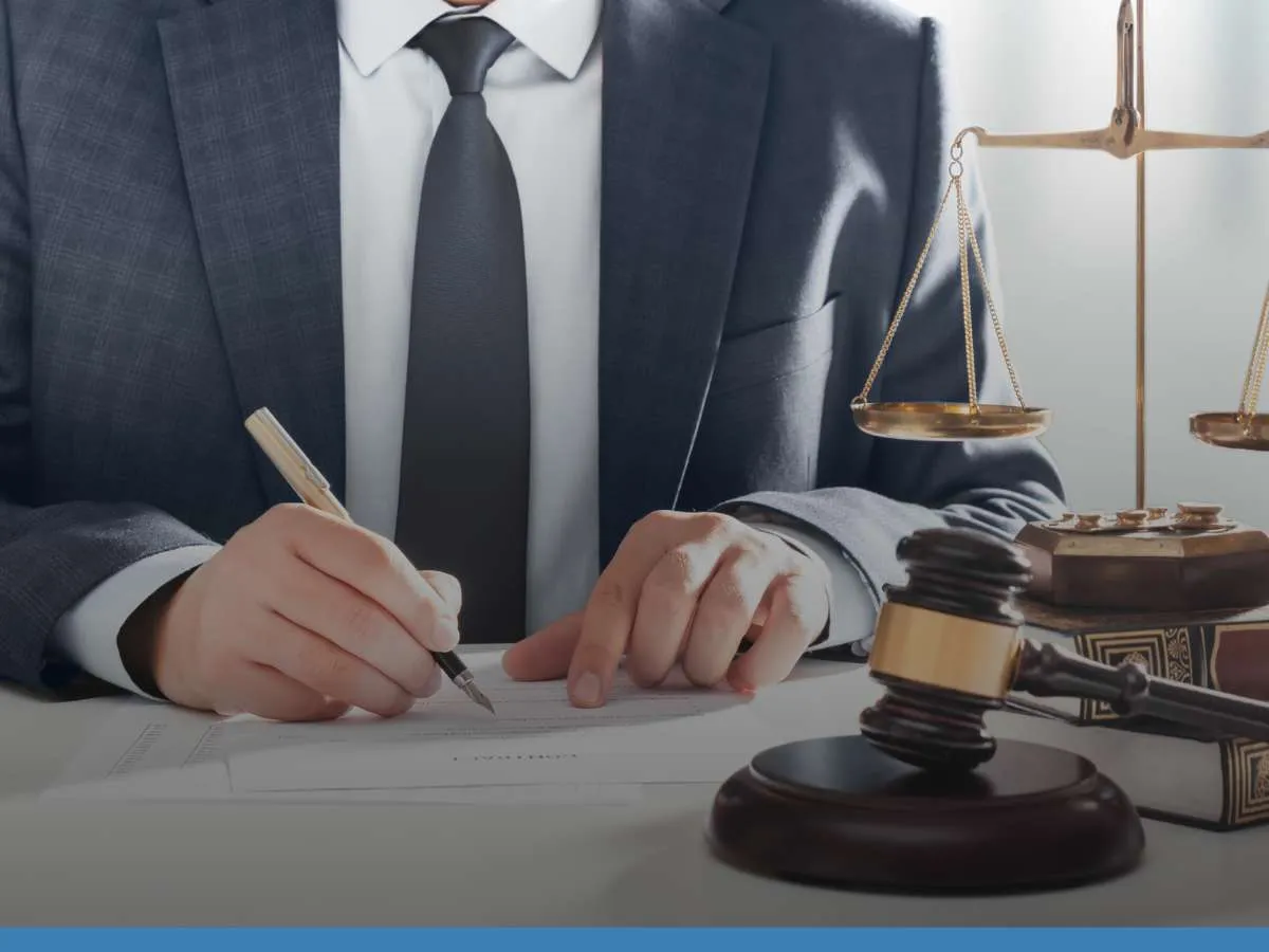 Lawyer signing documents next to a gavel and scales of justice, symbolizing legal defense for DUIs